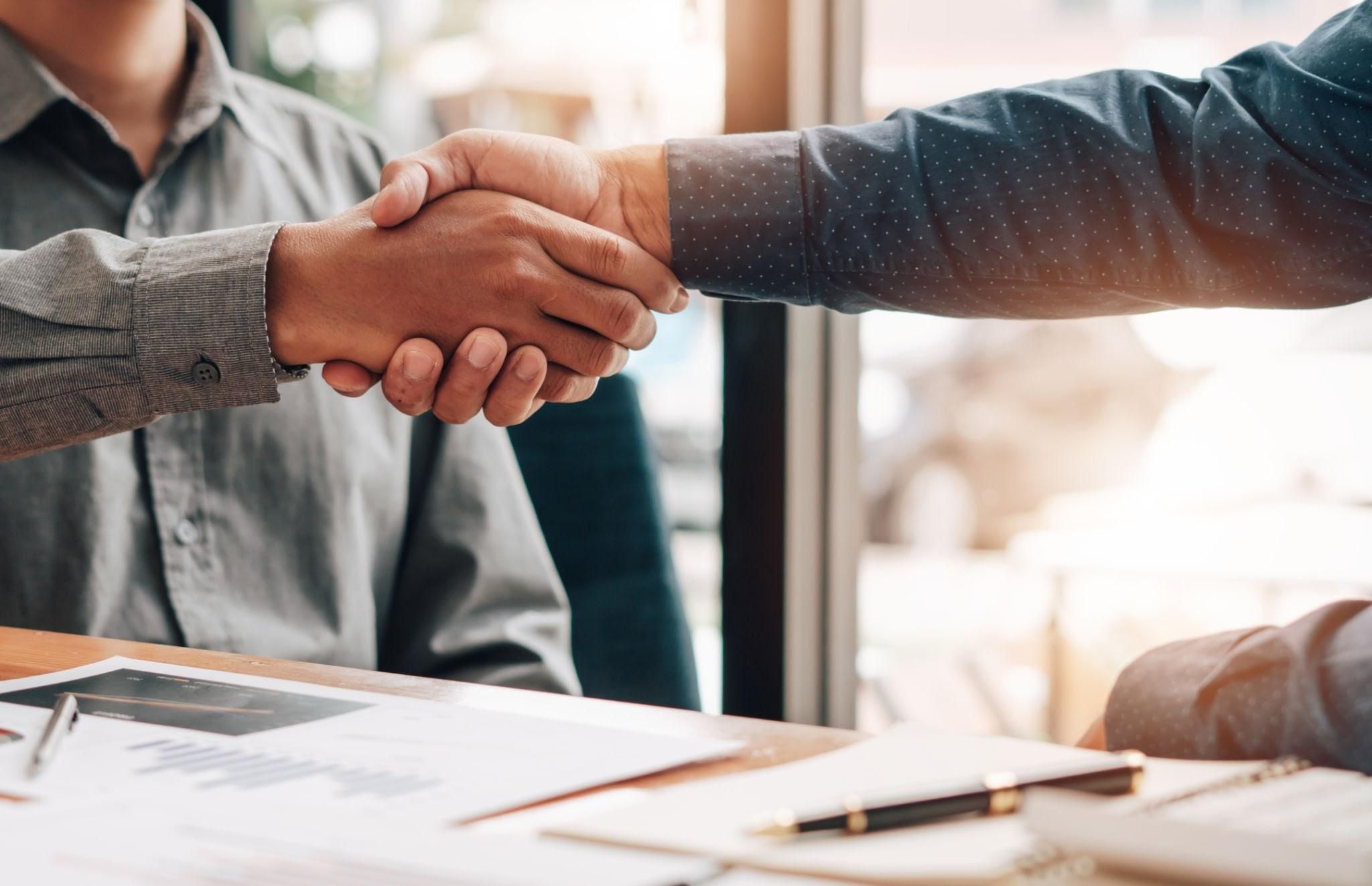 Dos profesionales estrechando la mano en una reunión